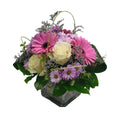 Arrangement en gerberas roses, roses blanches et marguerites, dans un vase de verre